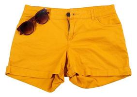 Pantalones cortos de color naranja y gafas de sol aislado sobre fondo blanco. foto