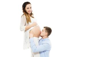 Hermosa joven pareja feliz esperando bebé - hombre besando el vientre embarazado foto