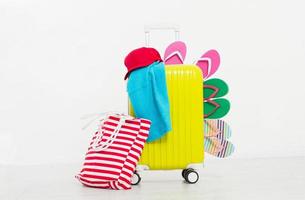 Yellow suitcase isolated on white background Summer holidays. summer flip flops or slippers.Sandals beach.Red cap.Travel valise or bag. Mock up. Copy space. Template. Blank. photo