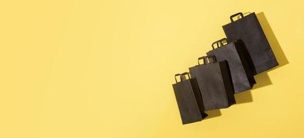 Bolsas de compras negras sobre fondo amarillo de venta de viernes negro con espacio de copia en formato de banner foto