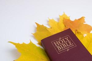 Holy bible with autumn leaf on white background photo