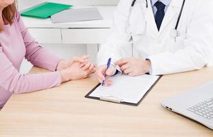 Patient listening intently to a male doctor explaining patient symptoms or asking a question as they discuss paperwork together in a consultation photo