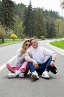 Stylish couple sitting on the road against the background of a beautiful park and green grass photo