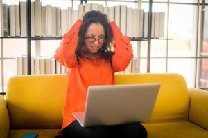 Latin woman working with laptop on sofa with stressed feeling photo