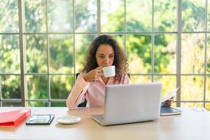 Latin woman working with coffee cup on working space photo