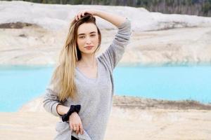 Beautiful teen woman posing at blue lake and yellow sand photo