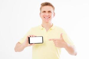 Hombre sonriente señala con la mano en la pantalla del teléfono aislado en blanco foto