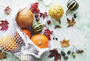 Autumn composition with assorted pumpkins in eco string bag photo