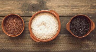 Vista panorámica de tres tazones de arroz orgánicos diferentes mesa de madera foto