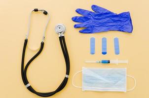 stethoscope crumpled gloves bandages syringe surgical gloves yellow background