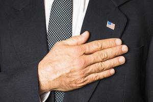 patriotic man  usa badge his black coat touching hand his chest