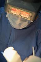 Close-up of the face of a surgeon operating with visual mask and mask cover. photo