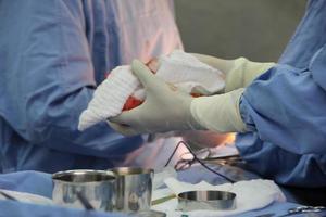 Primer plano de las manos del médico sosteniendo un algodón con sangre en la cirugía. foto
