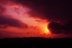 Red sunset with the sun behind the clouds photo