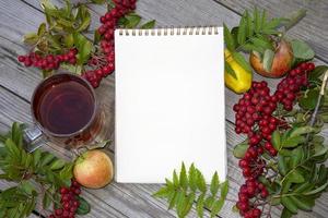 Blank paper for text, rowan berries, pears and apples on a wooden background. Background banner with notepad. photo