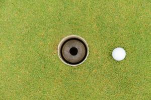 Golf hole and golf ball on green grass on golf course photo