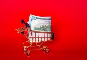 Trolley and money. Financial crisis or shopaholic concept. Mini shopping cart with money dollars. photo