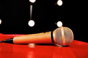 gold microphone on red wooden and dark backgrounds with many lights photo