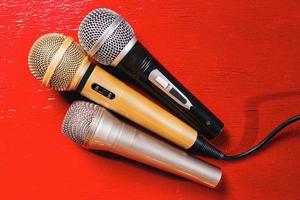 gold, silver and bronze microphones on red wooden background