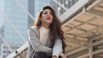 Lay off. Sacked. Fired business woman sitting on stairs of office building outside. photo