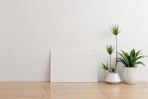 Maqueta de marco de fotos horizontal blanco en una habitación vacía de pared blanca con plantas en un piso de madera