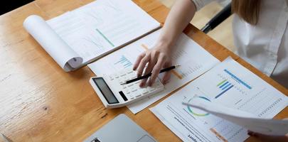 Business woman using calculator for do math finance on wooden desk in office and business working background, tax, accounting, statistics and analytic research concept photo