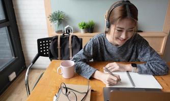 Cropped shot smiling asian woman freelancer wearing headset, communicating with client via video computer call. Millennial pleasant professional female tutor giving online language class photo
