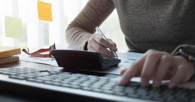 woman working with calculator for financial document in office. male accountant doing accounting and calculating. bookkeeper making calculation. Savings, finance photo