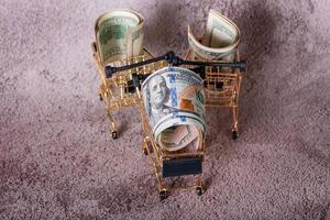 Three shopping baskets with dollars in them on a gray background. Financial concept. photo