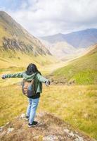 La parte trasera de una mujer feliz en un lugar pintoresco disfruta de un panorama escénico de la montaña de Kazbegi. viajar en el cáucaso. foto