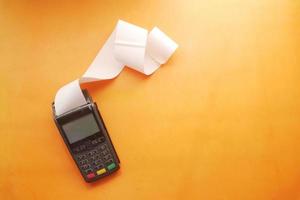 POS machine and long roll paper on orange background