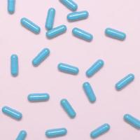 Blue pills on pink background close up