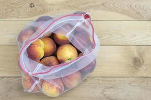 Peaches closeup in a grocery bag on a wooden background