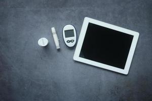 Vista superior de la tableta digital y la herramienta de medición de la diabetes en la mesa foto
