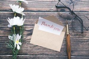 thank you message and envelope on wooden table photo