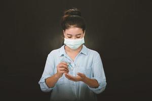 una foto de una niña en el estudio que lleva una mascarilla protectora contra la infección por coronavirus y se limpia las manos con gel desinfectante.