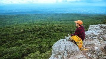 Freedom traveler woman enjoying a looking at mountain nature on the cliffs against beautiful scenery during summer journey relaxing outdoors. travel backpack photo