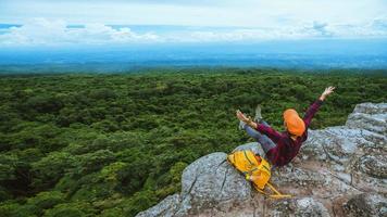 mujer de viajero de libertad disfrutando de una mirada a la naturaleza de la montaña en los acantilados contra hermosos paisajes durante el viaje de verano relajándose al aire libre. mochila de viaje foto