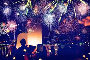 Fuegos artificiales con siluetas de personas en eventos de vacaciones.Fuegos artificiales de año nuevo en la playa. los viajeros y la gente celebran el día de año nuevo en kamala beach phuket, tailandia. foto