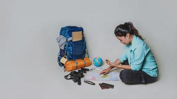 Tourist planning vacation with the help of world map with other travel accessories around. Woman traveler with suitcase on white background. Concept travel backpack