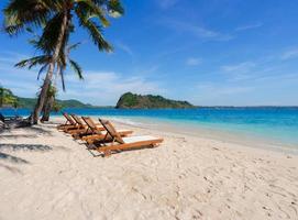beautiful scenic chairs on white sand beach near coconut trees with blue sea and sky on island photo