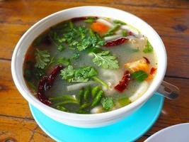 spicy Asian retail catfish soup with vegetables on wooden table