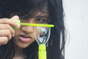 A girl holding a bubble maker and blowing them out. photo