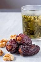 The large date fruits with walnut and tea in a glass on a marble floor photo
