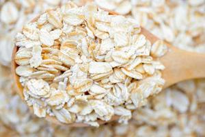 Close-up rolled oats in a wooden spoon on rolled oats pile is a healthy whole grain food. photo