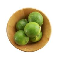 green lemon in wooden cup on white background photo