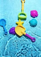juguetes de playa para niños sobre salpicaduras de agua. foto