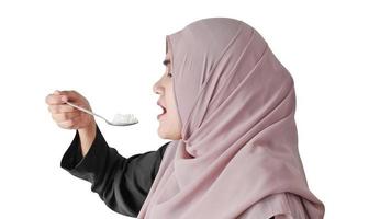 Muslim woman eating rice with spoon on white background. Healthy eating concept. photo