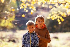 dos niños hermanos sobre un fondo de follaje otoñal foto