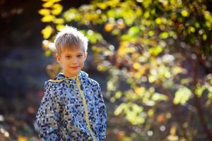 Retrato de un lindo niño sobre un fondo de follaje otoñal foto